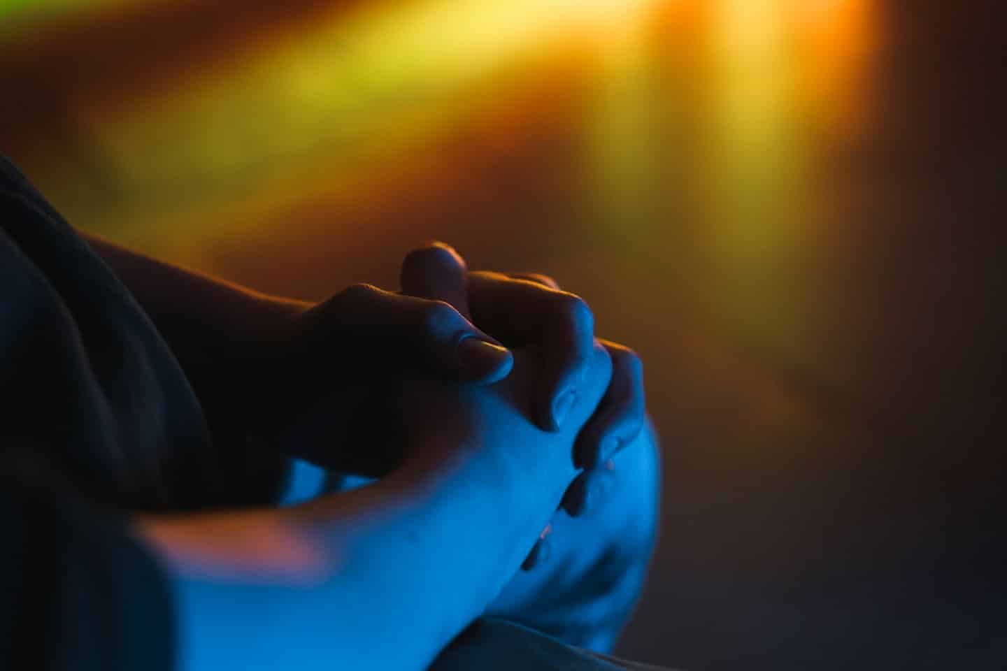 Person's hands clasped in prayer or meditation.